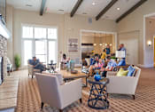 Thumbnail 13 of 15 - a group of people sitting in a living room with a fireplace at The Winhall of Williams Pointe Apartments, Waukee, IA