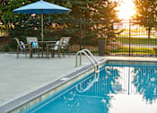 Thumbnail 15 of 15 - a swimming pool with an umbrella and a table with chairs at The Winhall of Williams Pointe Apartments, Waukee, IOWA
