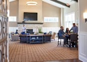 Thumbnail 6 of 15 - a large lobby with people sitting at tables and chairs at The Winhall of Williams Pointe Apartments, Waukee, IOWA
