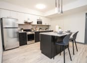 Thumbnail 9 of 13 - a kitchen with stainless steel appliances and a island with chairs