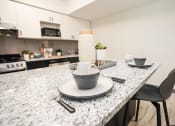 Thumbnail 8 of 13 - a kitchen with a marble counter top with plates and bowls on it