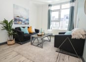 Thumbnail 6 of 13 - a living room with black furniture and a large window