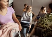 Thumbnail 16 of 17 - A group of people are gathered in a room, with one person holding a suitcase.