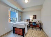 Thumbnail 29 of 33 - A bedroom with a bed, desk, and chair.