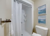 Thumbnail 28 of 33 - A white bathroom with a shower curtain and a towel hanging on a towel rack.
