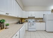 Thumbnail 20 of 33 - A white kitchen with a sink, stove, and refrigerator.