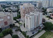 Thumbnail 1 of 17 - A large apartment complex sits in the middle of a city.