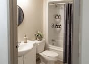 Thumbnail 11 of 17 - A white sink and toilet in a bathroom with a shower curtain.