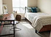 Thumbnail 14 of 17 - A bedroom with a bed, desk, and chair.