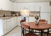 Thumbnail 9 of 17 - A kitchen with white cabinets and a wooden table.