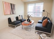 Thumbnail 8 of 17 - A living room with a black couch, a coffee table, and a painting on the wall.