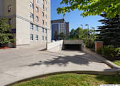 Thumbnail 7 of 17 - A parking lot in front of a building with a tall tree on the right.