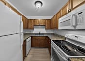 Thumbnail 6 of 21 - A kitchen with a white refrigerator, microwave, and stove.