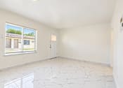 Thumbnail 8 of 19 - A room with white walls and marble flooring with a window showing a view of a house.
