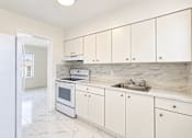 Thumbnail 16 of 19 - A kitchen with white cabinets and marble countertops.