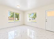 Thumbnail 9 of 19 - A room with a white door and windows with a view of the outside.