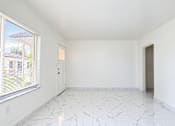 Thumbnail 15 of 19 - A room with white walls and marble flooring with a window on the left.