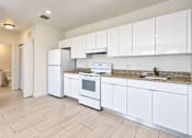 Thumbnail 23 of 48 - A kitchen with white appliances and cabinets.