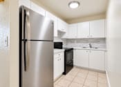 Thumbnail 17 of 26 - A kitchen with a stainless steel refrigerator and white cabinets.