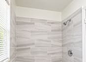Thumbnail 17 of 19 - A bathroom with a shower area and a white tile floor.