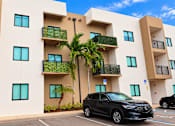 Thumbnail 10 of 48 - A black SUV is parked in a parking lot in front of a white building with balconies.