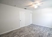 Thumbnail 6 of 15 - an empty living room with a ceiling fan and a white door
