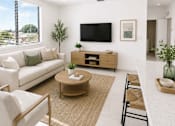Thumbnail 2 of 25 - A living room with a white couch, a coffee table, and a flat screen TV mounted on the wall.