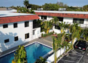Thumbnail 12 of 21 - A white building with a red roof and a pool in the foreground.