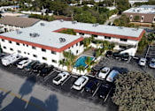 Thumbnail 18 of 21 - A parking lot with a white building with a red roof.