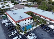 Thumbnail 1 of 21 - A large white building with a red roof and a pool in the courtyard.