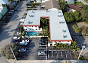 Thumbnail 3 of 21 - A parking lot with a building and a pool in the background.