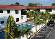 Thumbnail 5 of 21 - A white building with a red roof and a pool in the foreground.