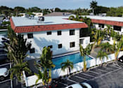 Thumbnail 8 of 21 - A white building with a red roof is surrounded by a parking lot.