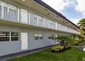 Thumbnail 11 of 15 - A white building with a balcony and a white door.