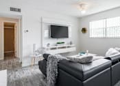 Thumbnail 5 of 15 - A black leather sofa with a grey throw blanket on it in a living room.