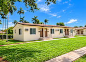 Thumbnail 3 of 19 - A row of houses with green lawns and trees in the background.