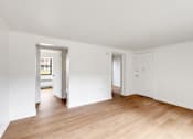 Thumbnail 18 of 49 - A room with white walls and wooden flooring with two doors.