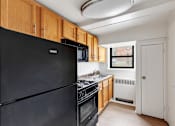 Thumbnail 16 of 49 - A black fridge in a kitchen with wooden cabinets.
