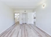 Thumbnail 13 of 26 - A long hallway with white walls and wood flooring.