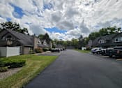 Thumbnail 2 of 2 - A residential street with houses on both sides and cars parked on the right side.