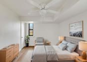 Thumbnail 13 of 49 - A bedroom with a large bed, a ceiling fan, and a painting on the wall.