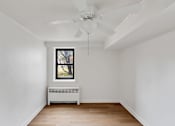 Thumbnail 32 of 49 - A room with a ceiling fan and a window with a view of trees.