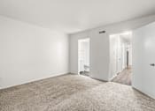 Thumbnail 18 of 29 - A spacious, empty room with white walls and carpeted floor.