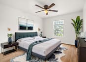 Thumbnail 5 of 31 - A bedroom with a bed, a ceiling fan, and a window.