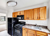 Thumbnail 15 of 49 - A kitchen with wooden cabinets and black appliances.