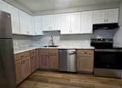 Thumbnail 7 of 38 - A kitchen with white cabinets and a wooden floor.