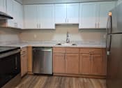 Thumbnail 1 of 16 - A kitchen with wooden cabinets and a stainless steel dishwasher.