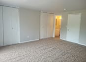 Thumbnail 8 of 17 - A room with white walls and carpeted floor with a door on the right.