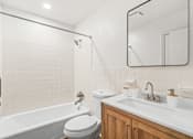 Thumbnail 19 of 28 - A white bathroom with a tub, toilet, sink, and mirror.