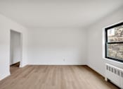 Thumbnail 24 of 49 - A room with wooden floors and a window showing trees outside.